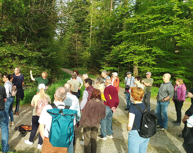 Männer und Frauen stehen in einer Gruppe und hören Forstrevierleiterin Karin Beer zu.
